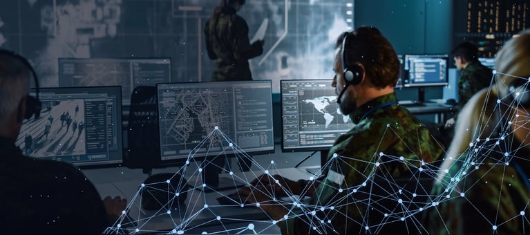 Man in uniform at desk looking at multiple monitors